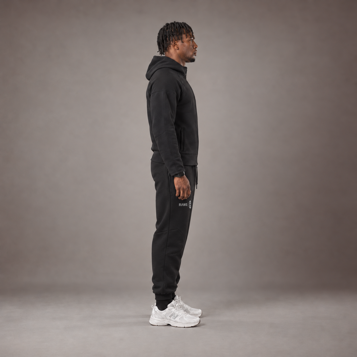 Model wearing the RAWS Basketball Tech Hoodie and Tech Pants in Black, side view