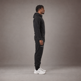 Model wearing the RAWS Basketball Tech Hoodie and Tech Pants in Black, side view