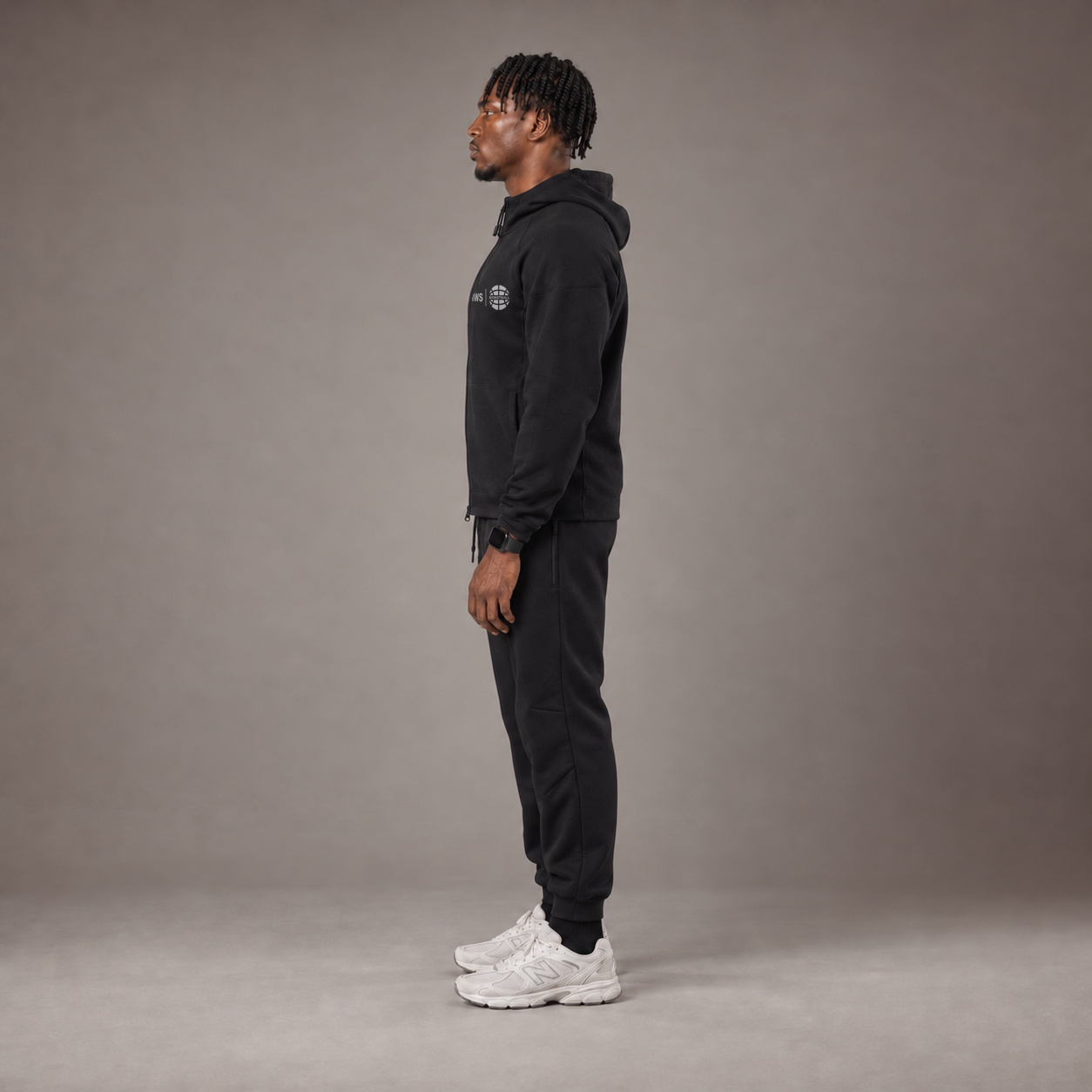 Model wearing the RAWS Basketball Tech Hoodie and Tech Pants in Black, side view
