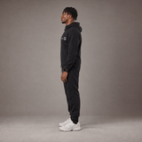 Model wearing the RAWS Basketball Tech Hoodie and Tech Pants in Black, side view