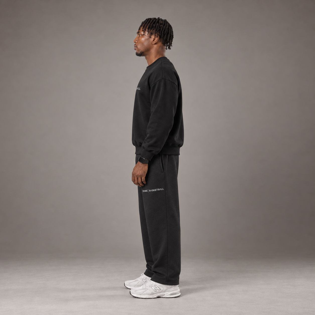 Model wearing the RAWS Off-Court Crew Sweatshirt and Joggers in Black, side view